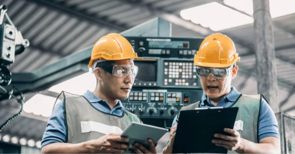 Trabalhadores industriais com óculos de proteção mostrando quando o PCMSO é obrigatório.
