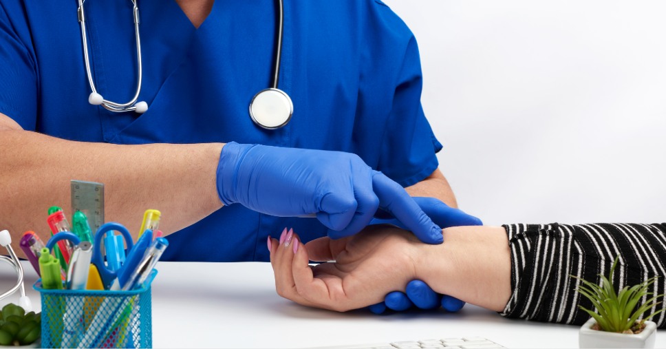 Monitoramento da saúde ocupacional durante a avaliação do pulso de uma paciente por um profissional de saúde.